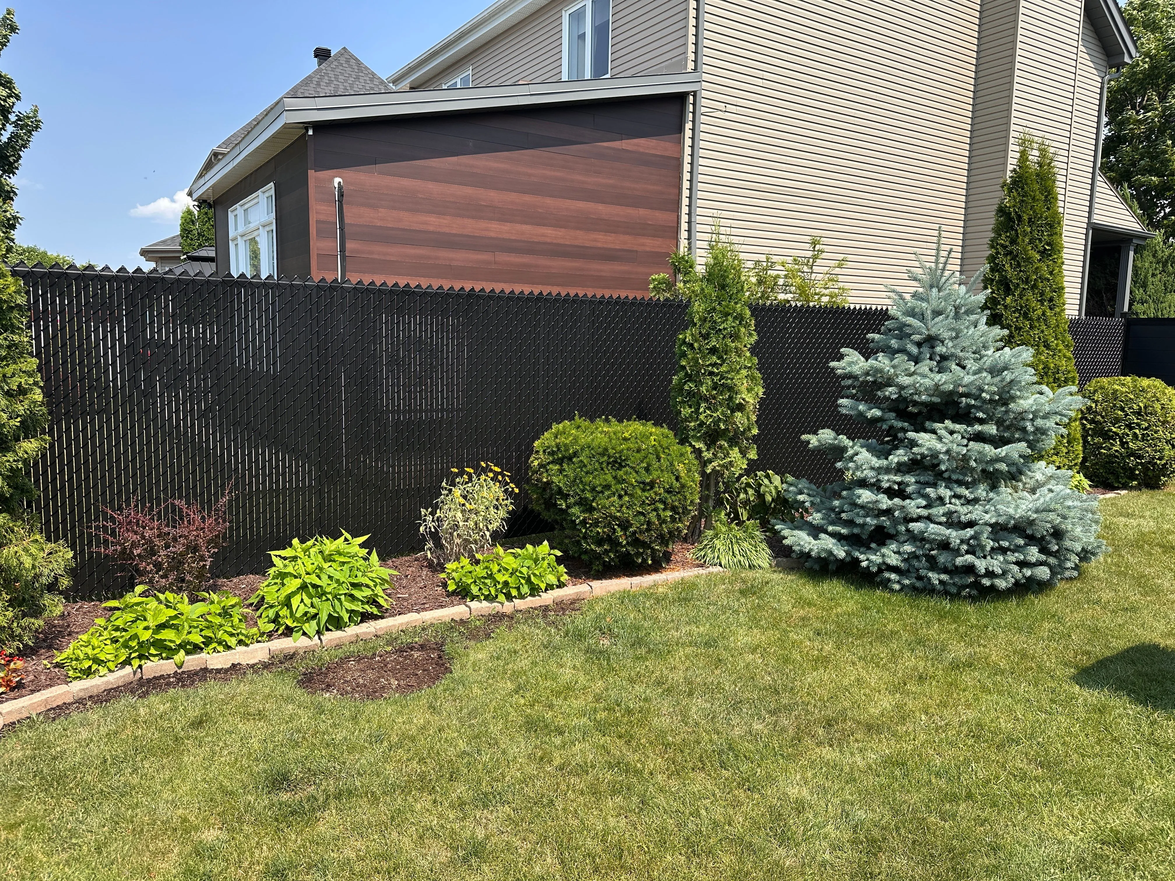Clôture en maille de chaîne noire avec lattes d'intimité et aménagement paysager