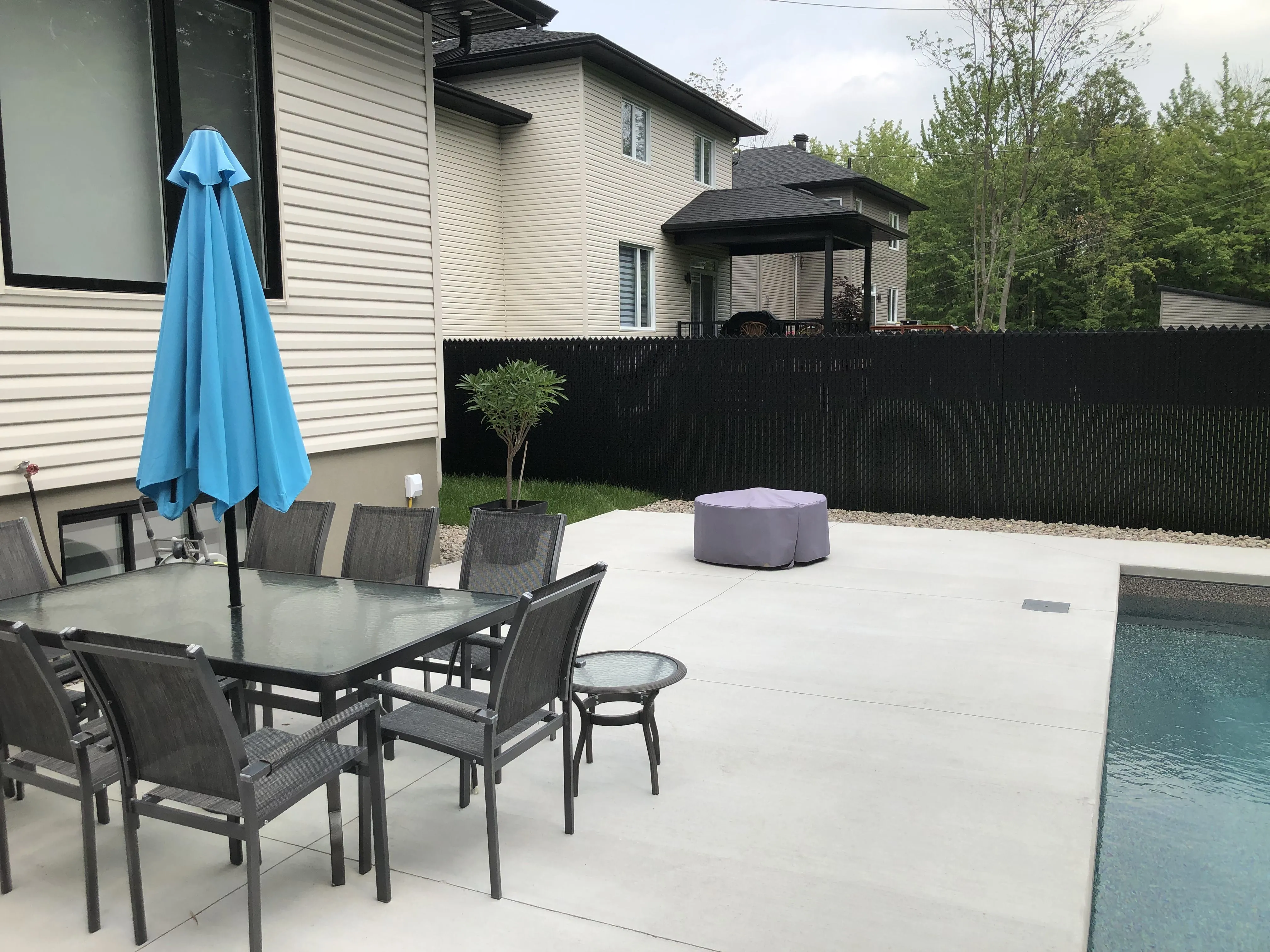 Cour arrière avec terrasse, piscine et clôture en maille de chaîne avec lattes d'intimité