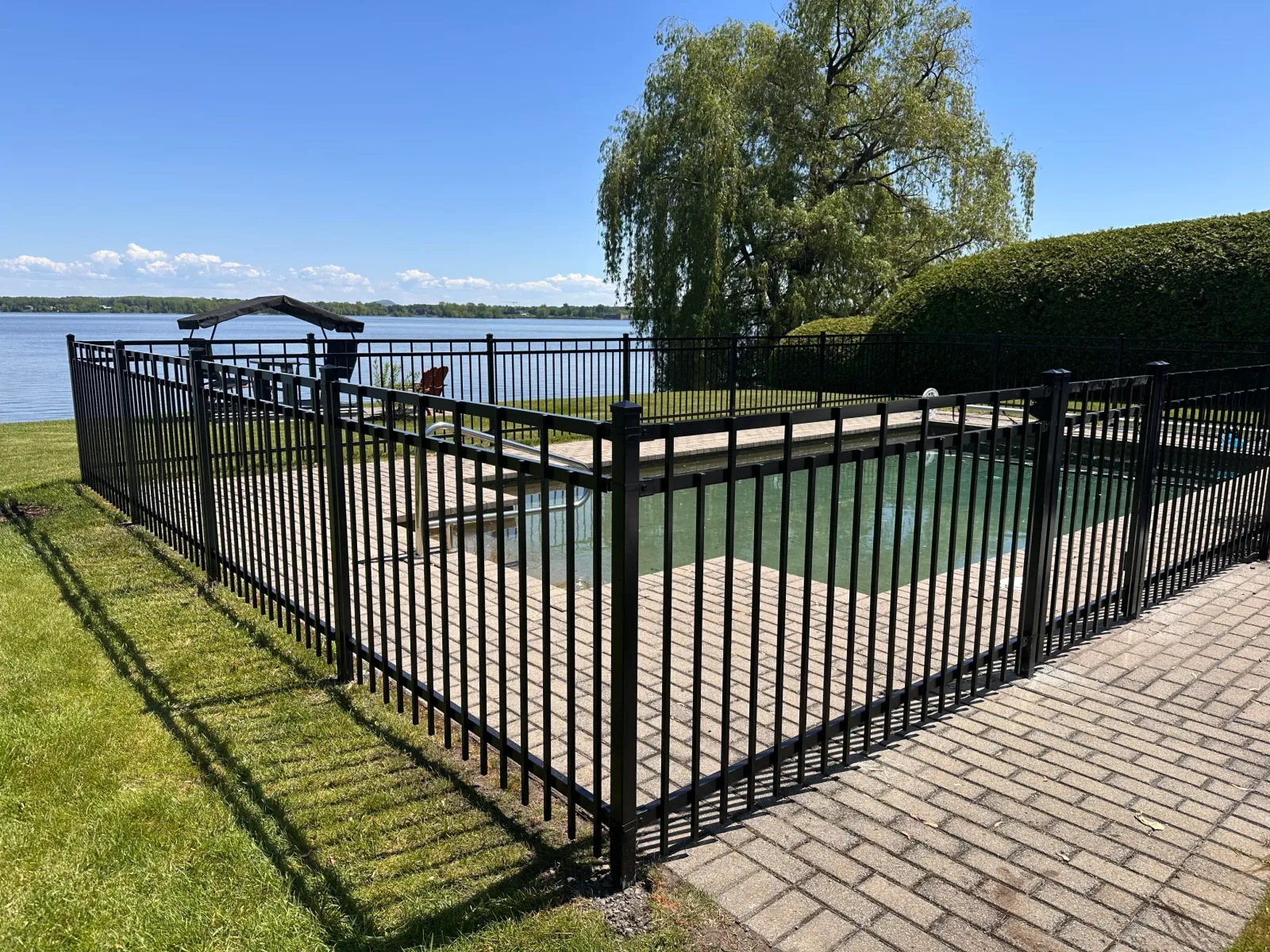 Clôture ornementale noire autour d'une piscine en bord de lac