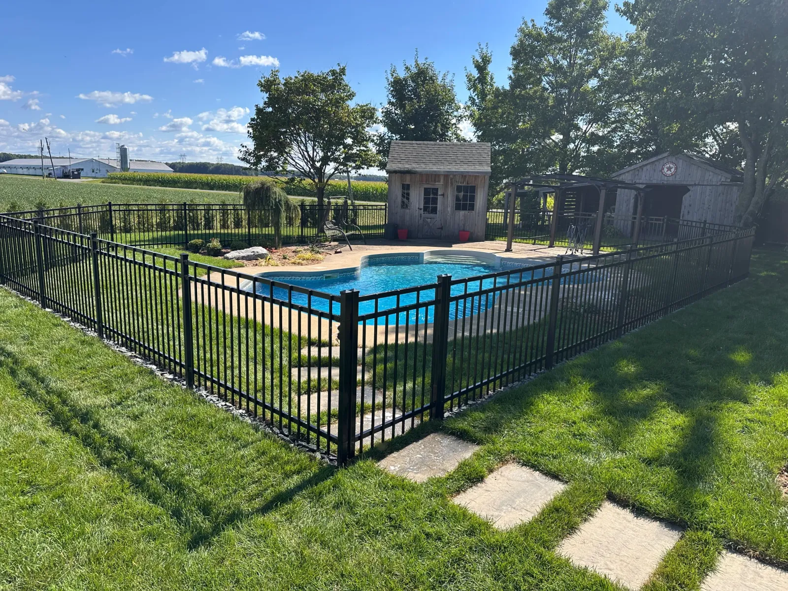 Clôture ornementale noire autour d'une piscine en campagne